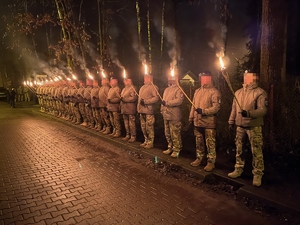 policjanci w szeregu z płonącymi pochodniami w dłoniach