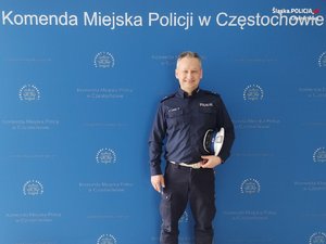 umundurowany policjant stoi na tle ścianki Komendy Miejskiej Policji w Częstochowie