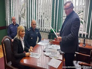 osoby podpisujące akt notarialny siedzą za biurkiem i podpisują dokumenty