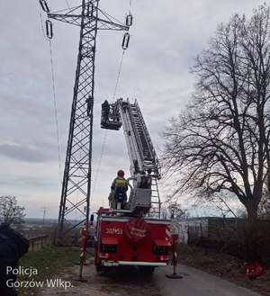 Wóz strażacki z wysięgnikiem jadącym na górę słupa energetycznego