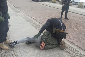 policjant trzyma leżącego na ziemi zatrzymanego