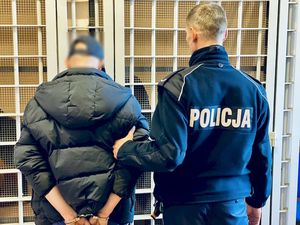 policjant prowadzi zatrzymanego - widok z tyłu