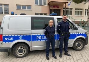 Dwóch policjantów stoi przed radiowozem