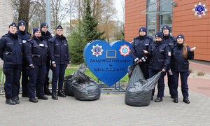 umundurowani policjanci stoją przy sercu Zarząd NSZZ Policjantów w Szkole Policji w Pile przed nimi stoją worki z nakrętkami