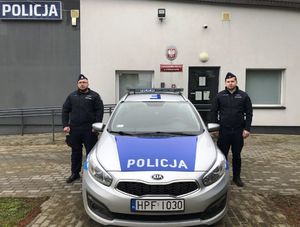 dwaj policjanci stoją przy radiowozie