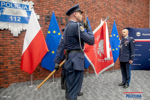 policjant ze sztandarem. przed nim stoi Komendant Główny Policji