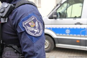 Ramię policjanta stojącego przy radiowozie