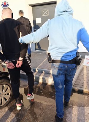 policjant prowadzi zatrzymanego mężczyznę