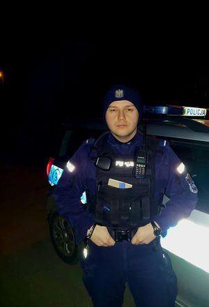 noc. policjant stoi przy radiowozie