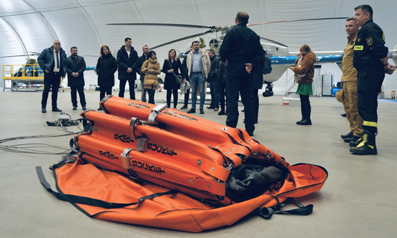 Uczestnicy szkolenia w hangarze śmigłowcowym, na pierwszym planie zbiornik Bambi Bucket.