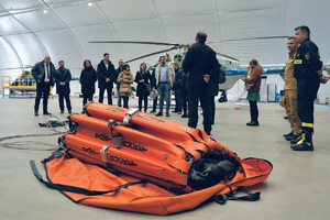 Uczestnicy szkolenia w hangarze śmigłowcowym, na pierwszym planie zbiornik Bambi Bucket.