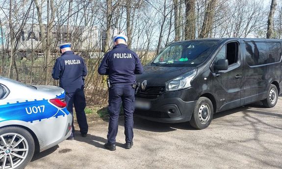 dwaj umundurowani policjanci kontrolują auto