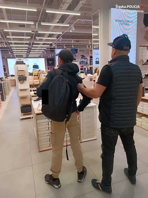 ubrany po cywilnemu policjant w czasie wolnym z zatrzymanym mężczyzną w sklepie - widok z tyłu