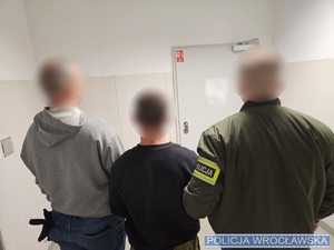 dwaj funkcjonariusze z zatrzymanym