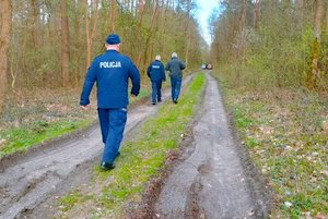 droga w lesie, idą nią policjanci