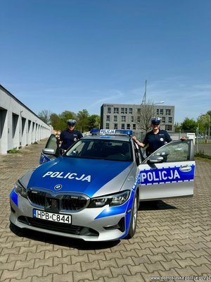 Dwaj umundurowani policjanci przy radiowozie