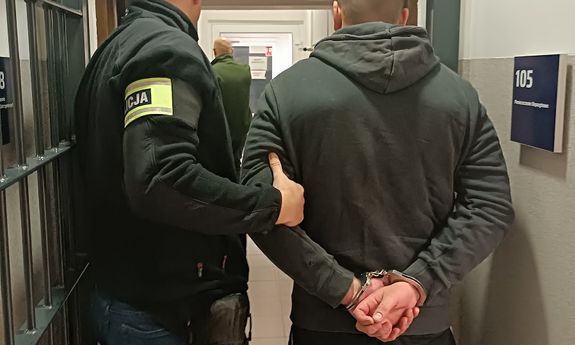 policjant prowadzi zatrzymanego