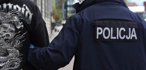 umundurowany policjant prowadzi zatrzymanego mężczyznę