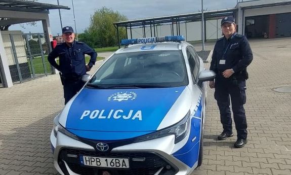 radiowóz, obok stoją policjanci