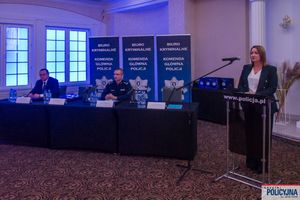 stół prezydialny i prelegentka przy mównicy podczas konferencji