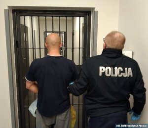umundurowany policjant prowadzi zatrzymanego mężczyznę