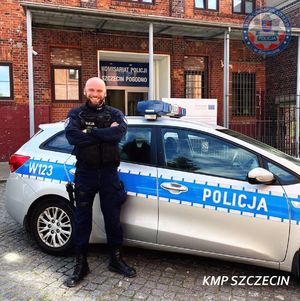 policjant stoi przy radiowozie