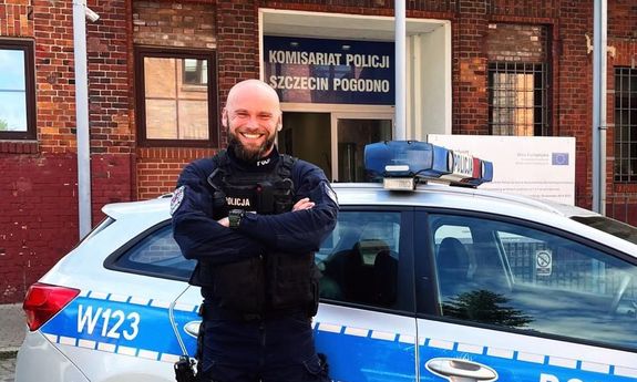 policjant stoi przy radiowozie