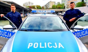 policjanci stoją po dwóch stronach radiowozów