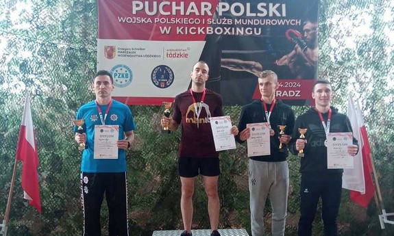 czterech mężczyzn na podium, każdy z nich trzyma dyplom i puchar za udział w zawodach