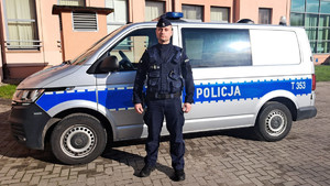 umundurowany policjant stoi przy radiowozie