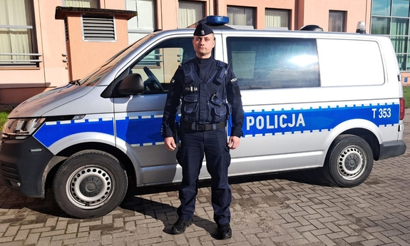 umundurowany policjant stoi przy radiowozie