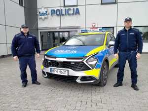 dwóch policjantów stoi koło radiowozu