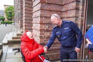 Chłopak na wózku inwalidzkim wita się z policjantem