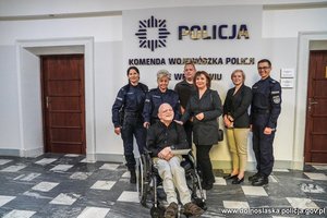 wspólne zdjęcie Chłopaka na wózku inwalidzkim z policjantami i pracownicą cywilną oraz opiekunami