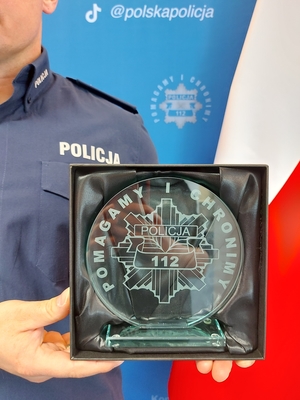 szklana statuetka z logiem Pomagamy i chronimy trzymana w dłoniach policjanta