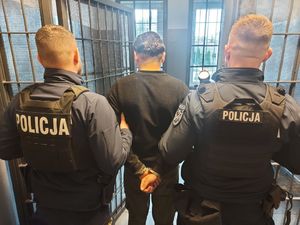 dwaj policjanci z zatrzymanym zakutym w kajdanki