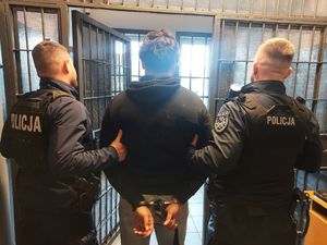 dwaj policjanci z zatrzymanym zakutym w kajdanki