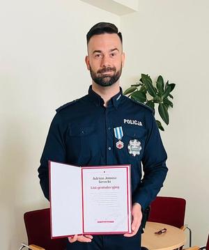 policjant trzyma list gratulacyjny