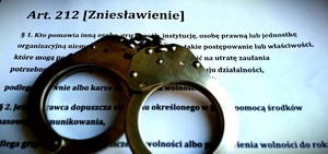 kajdanki leżą na kartce, na której jest wydrukowana definicja zniesławienia