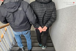 policjant z zatrzymanym idą po schodach w dół