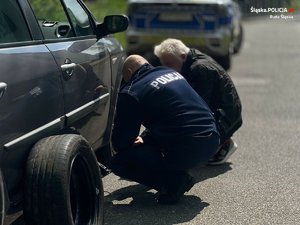 policjant wymienia koło w samochodzie seniora, on obok, a w tle radiowóz