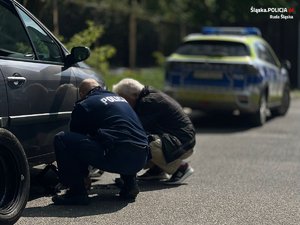 policjant wymienia koło w samochodzie seniora, on obok, a w tle radiowóz