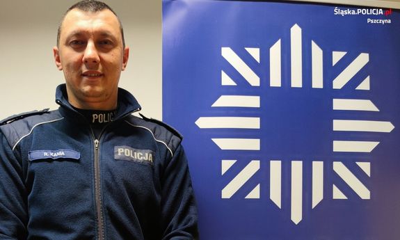 umundurowany dzielnicowy stoi przy ściance ze znakiem graficznym Policji, pod którym widnieje napis: Policja