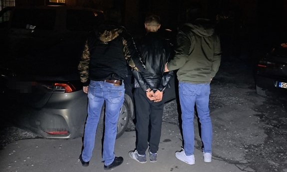 dwaj nieumundurowani funkcjonariusze z zatrzymanym w kajdankach