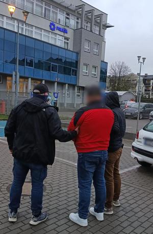 Zatrzymany mężczyzna prowadzony przez nieumundurowanych policjantów