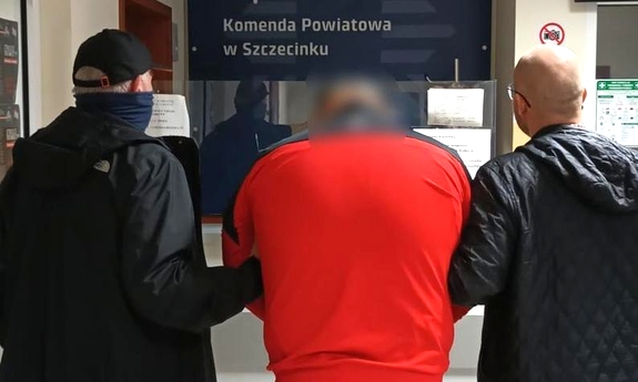 Zatrzymany mężczyzna prowadzony przez nieumundurowanych policjantów