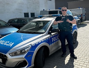 umundurowany policjant stoi przy radiowozie