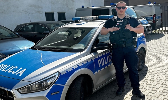 umundurowany policjant stoi przy radiowozie