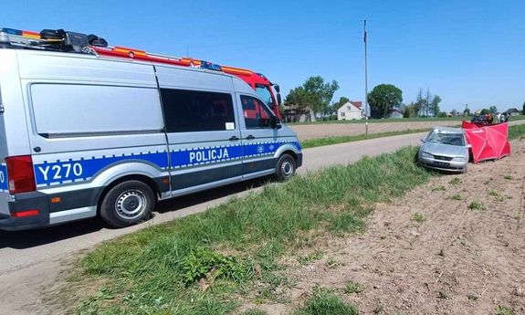 Miejsce wypadku drogowego w m. Wilkęsy. Policyjny radiowóz a przed nim rozstawiony czerwony namiot przy rozbitym samochodzie