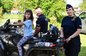 policjant i policjantka w umundurowaniu służbowym i dzieci siedzące na quadzie